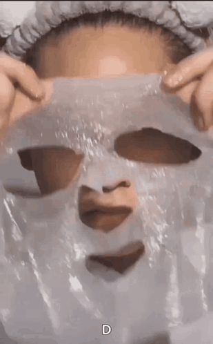 A Woman Is Wearing A Plastic Mask On Her Face With A Heart Cut Out Of It . GIF
