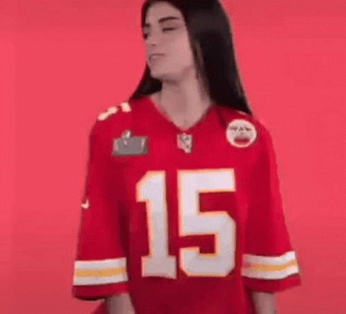 A Woman Is Wearing A Red Kansas City Chiefs Jersey And Smiling . GIF