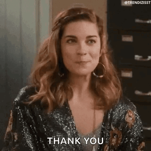 A Woman Is Wearing A Sequined Jacket And Earrings And Is Saying Thank You . GIF