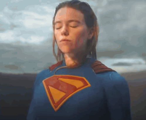 A Woman Is Wearing A Superman Costume With Her Eyes Closed . GIF