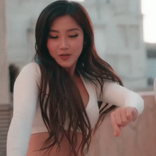 A Woman Is Wearing A White Crop Top And Giving A Thumbs Down Sign . GIF