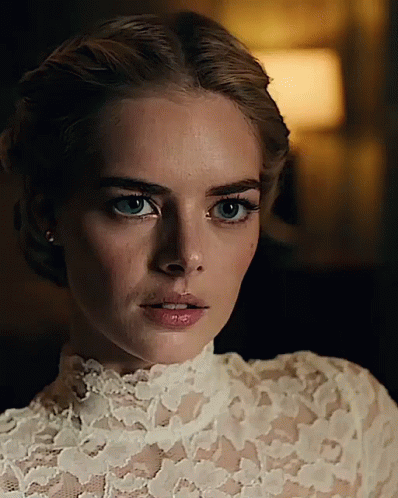 A Woman Is Wearing A White Lace Top And Earrings GIF
