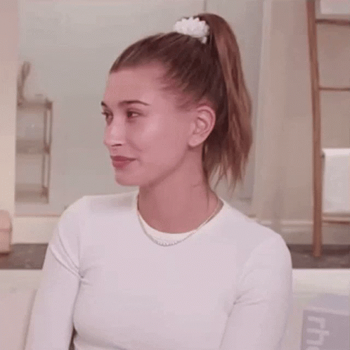 A Woman Is Wearing A White Shirt And A Ponytail . GIF