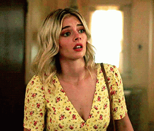 A Woman Is Wearing A Yellow Floral Top And A Brown Purse . GIF