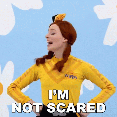 A Woman Is Wearing A Yellow Shirt That Says The Wiggles On It GIF