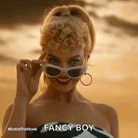 A Woman Is Wearing Sunglasses And Smiling While Standing On A Beach . GIF