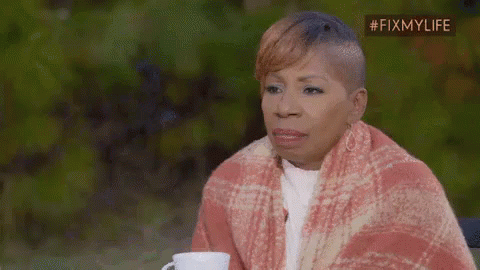 A Woman Is Wrapped In A Blanket And Holding A Cup . GIF