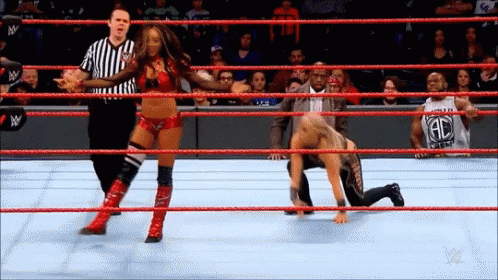 a woman is wrestling a man in a wrestling ring while a referee looks on .