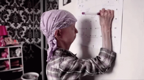 A Woman Is Writing On A Calendar With A Marker GIF