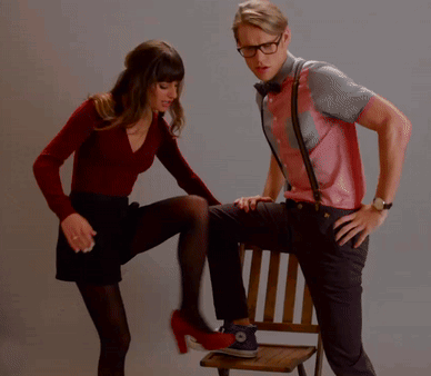 A Woman Kicking A Man 'S Leg Who Is Sitting In A Chair GIF