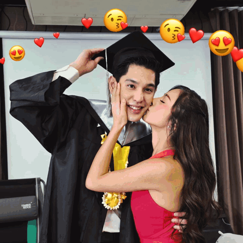 A Woman Kisses A Man In A Graduation Cap And Gown With Hearts Around Them GIF