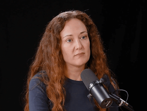 A Woman Laughs In Front Of A Microphone That Says Shure GIF