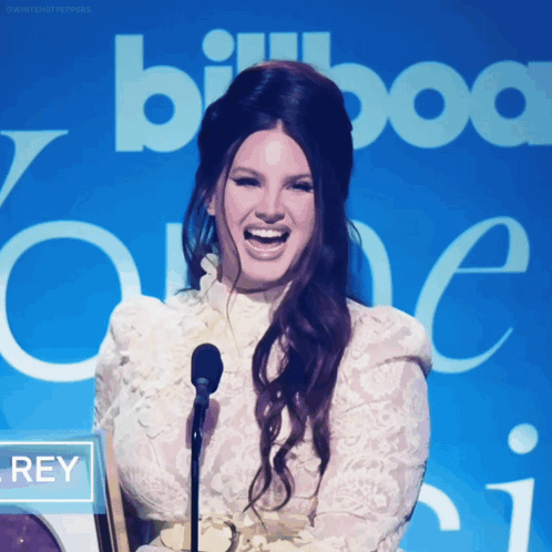 A Woman Laughs In Front Of A Sign That Says Billboard One GIF