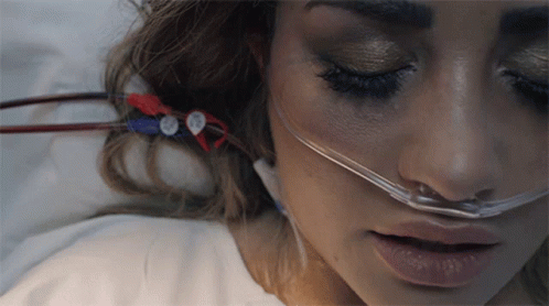 A Woman Laying In A Hospital Bed With An Oxygen Mask On Her Nose GIF