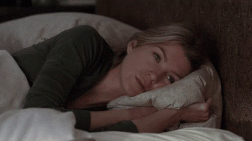 A Woman Laying In Bed With A Pillow On Her Head GIF