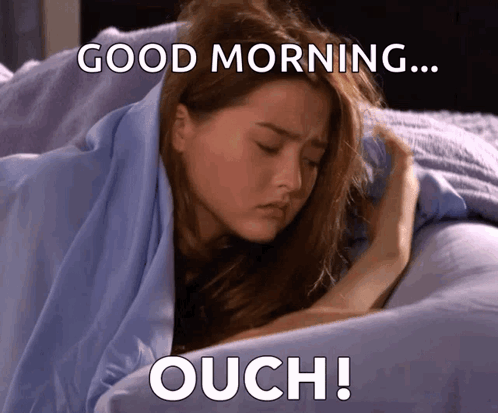 A Woman Laying In Bed With The Words Good Morning Ouch Written Below Her GIF