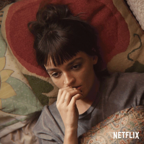 A Woman Laying On A Bed With A Netflix Logo On The Bottom GIF