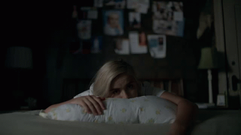 A Woman Laying On A Bed With A Pillow On Her Head GIF