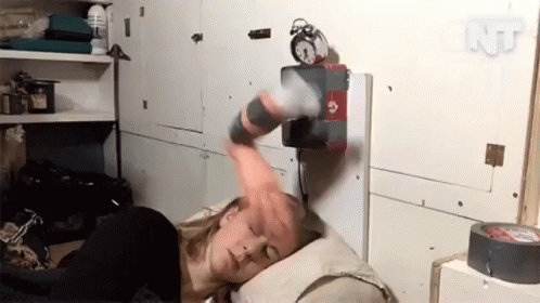 A Woman Laying On A Bed With An Alarm Clock On The Wall Above Her GIF
