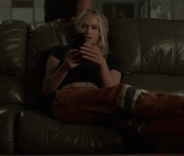A Woman Laying On A Couch Looking At Her Phone GIF