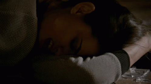 A Woman Laying On A Table With Her Head On Her Arm GIF