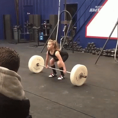 A Woman Lifts A Barbell In A Gym With A Sign That Says ' Awesome ' On It GIF