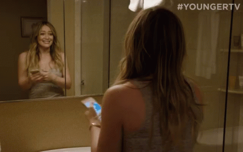 a woman looking at herself in a bathroom mirror with #youngertv on the bottom