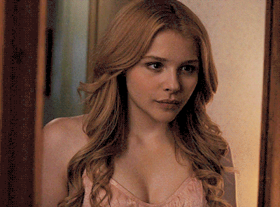 A Woman Looking At Herself In A Mirror While Wearing A Pink Top GIF