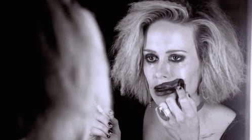 A Woman Looks At Herself In A Mirror With Lipstick On Her Lips GIF