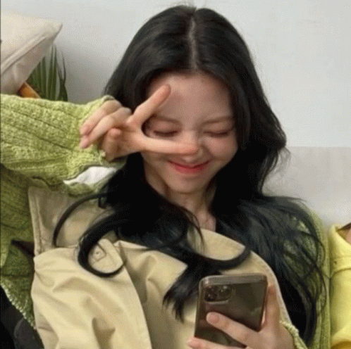 A Woman Making A Peace Sign While Holding A Phone GIF