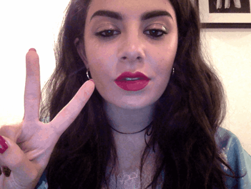 A Woman Making A Peace Sign With Her Hand GIF