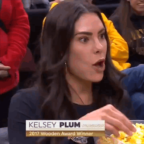 A Woman Named Kelsey Plum Is Sitting In A Crowd Eating Popcorn GIF