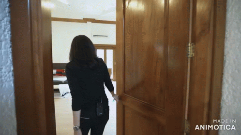 A Woman Opens A Wooden Door With The Words Made In Animatica On The Bottom GIF