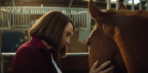 A Woman Petting A Horse In A Stable With The Words Dream Horse On The Fence GIF