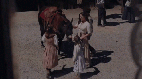 A Woman Petting A Horse While A Little Girl Stands Next To It GIF