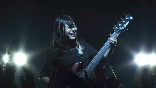 A Woman Playing A Guitar With A Yamaha Logo On The Headstock GIF