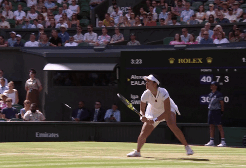 A Woman Playing Tennis In Front Of A Rolex Sign GIF