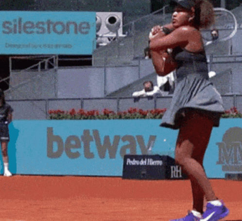 A Woman Playing Tennis In Front Of A Sign That Says ' Silestone ' On It GIF