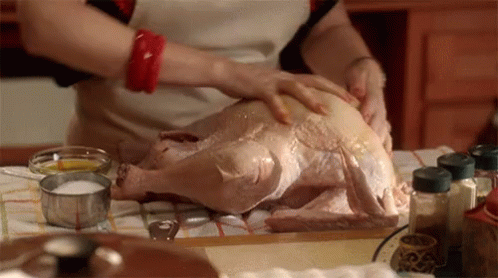 A Woman Prepares A Turkey In A Kitchen GIF