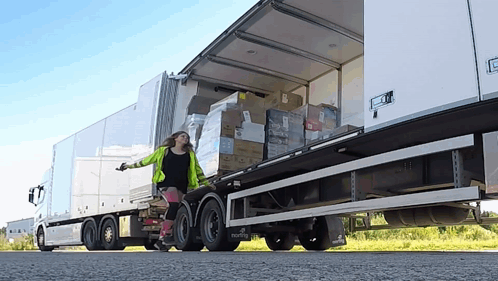 A Woman Pushes A Dolly In Front Of A Semi Truck That Says ' Martin ' On The Side GIF