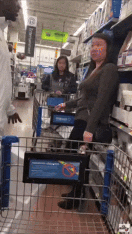 A Woman Pushing A Shopping Cart In A Store With A Sign That Says No Pets GIF