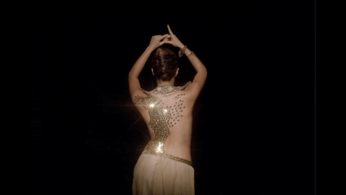 A Woman 'S Back Is Covered In Sequins And Has A Light Shining On Her GIF