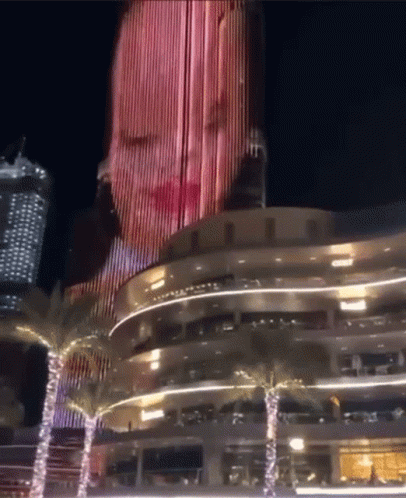 A Woman 'S Face Is Projected Onto The Side Of A Building GIF
