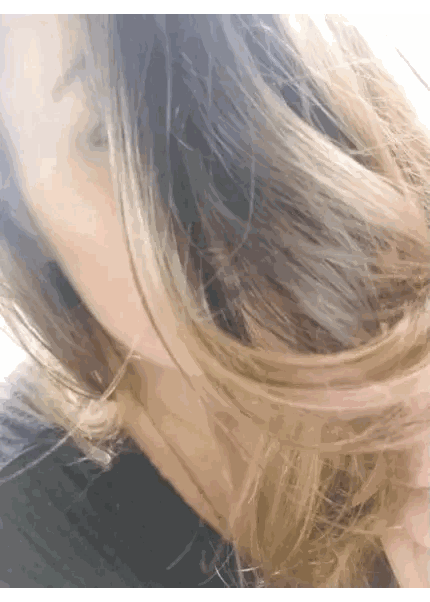 a woman 's hair is blowing in the wind and she is wearing a black shirt