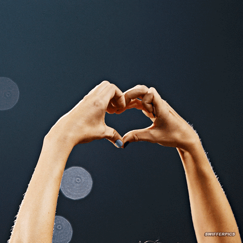 A Woman 'S Hands Are Making A Heart Shape With A Watermark That Says Swiferpics GIF