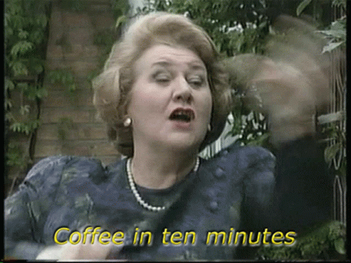 A Woman Says " Coffee In Ten Minutes " While Wearing A Pearl Necklace GIF