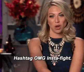 A Woman Says Hashtag Omg Insta-Fight In Front Of A Vase Of Flowers GIF