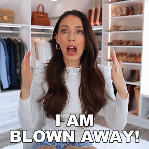 A Woman Says I Am Blown Away In Front Of A Closet Full Of Clothes GIF