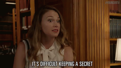 A Woman Says It 'S Difficult Keeping A Secret In Front Of A Bookshelf GIF