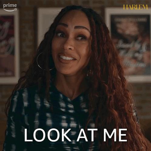 A Woman Says Look At Me In Front Of Some Framed Posters GIF